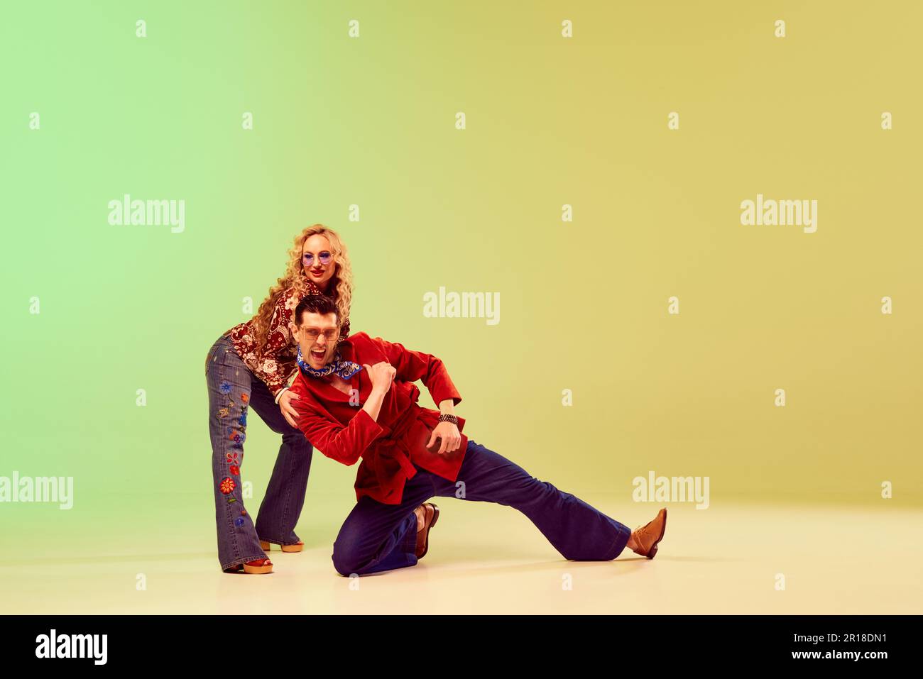 Emotionnel expressif homme beau et belle femme dans des ensembles de style vintage dansant sur fond dégradé vert jaune Banque D'Images