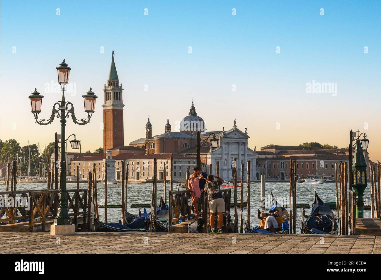 Photo prise d'un couple d'amoureux embrassant sur le front de mer du bassin de Saint-Marc avec l'île de San Giorgio Maggiore en arrière-plan, Venise Italie Banque D'Images