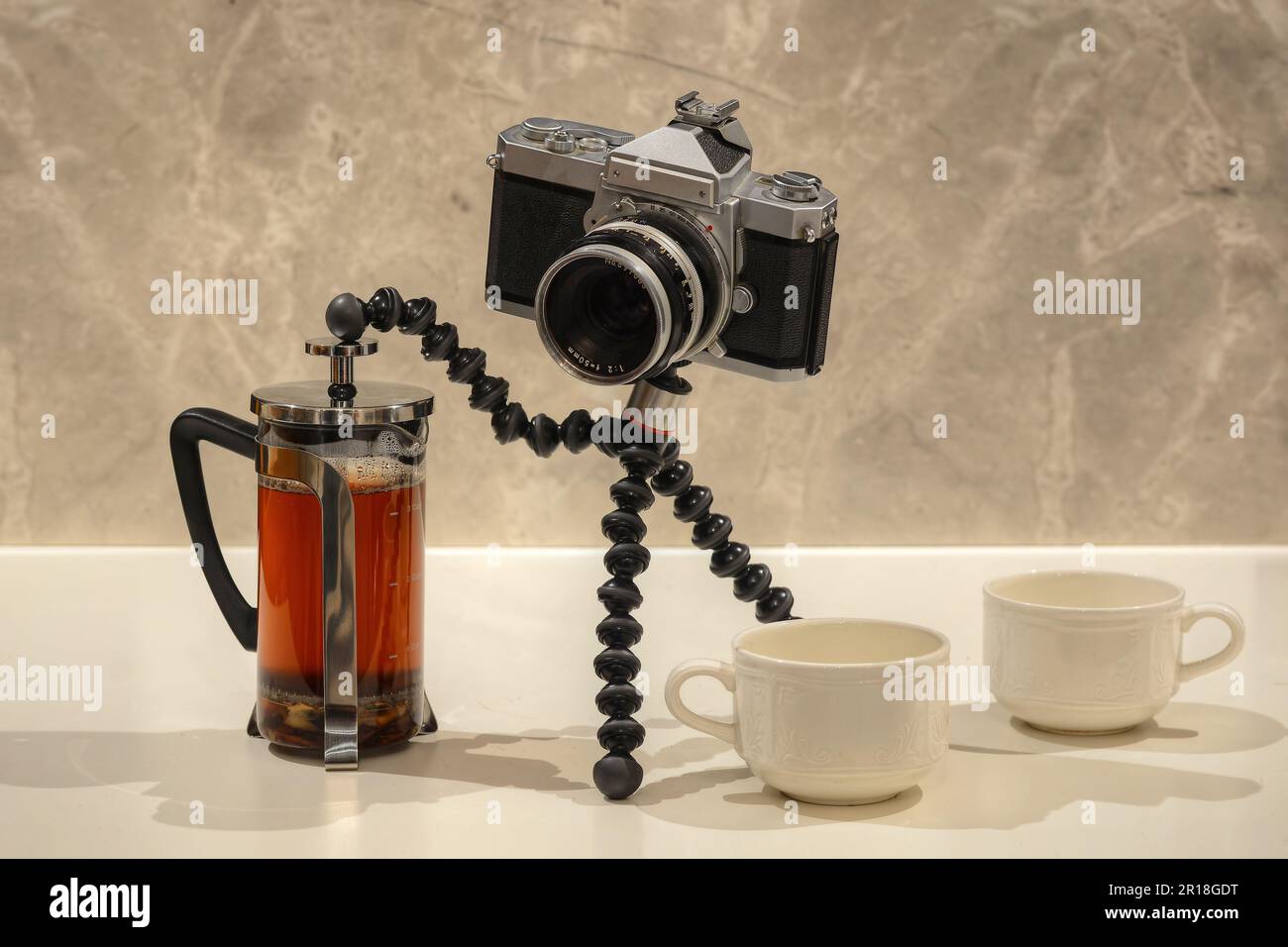 Une photo d'un vieil appareil photo reflex faisant du thé avec une presse française Banque D'Images