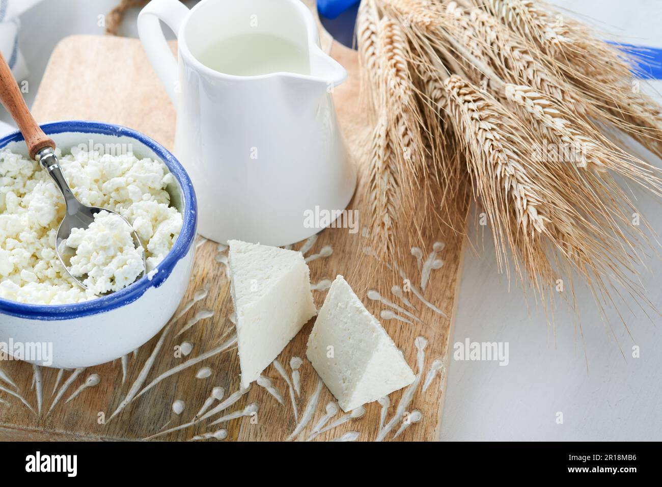 Fête juive de Shavuot. Kasher produits laitiers frais lait et fromage, blé mûr, crème sur fond de bois blanc. Les produits laitiers sur le whi Banque D'Images