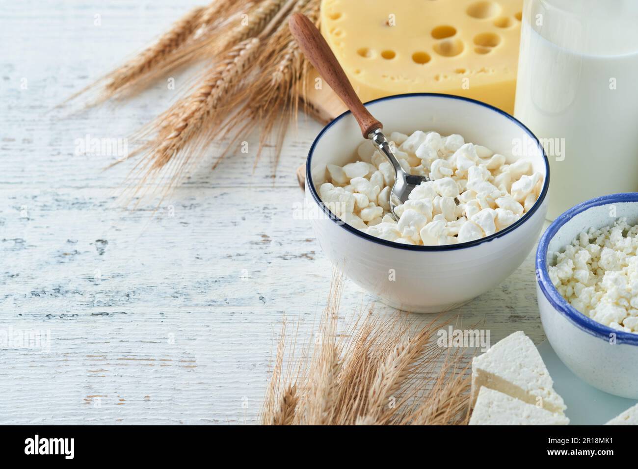 Fête juive de Shavuot. Kasher produits laitiers frais lait et fromage, blé mûr, crème sur fond de bois blanc. Les produits laitiers sur le whi Banque D'Images