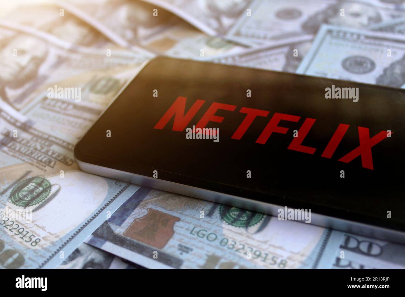 Logo Netflix affiché sur le smartphone au-dessus de la pile d'argent. Banque D'Images