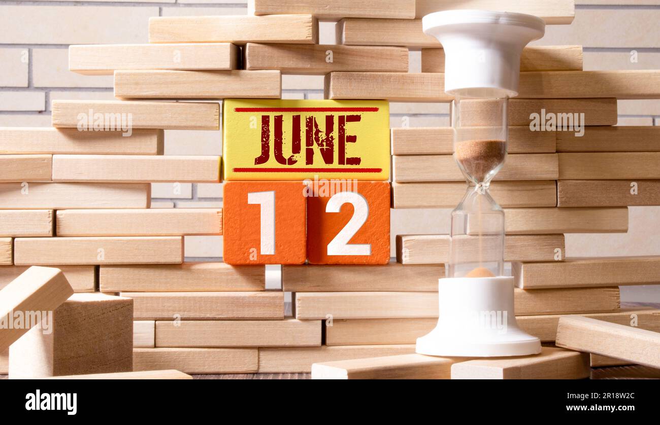 Texte de la date du calendrier 12 juin sur des blocs de bois avec un arrière-plan de nature flou. Concept d'espace de copie et de calendrier. Banque D'Images