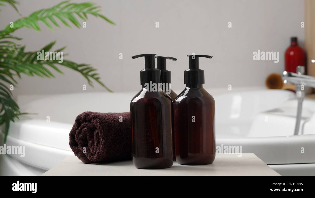 Mousse pour le bain et autres produits d'hygiène personnelle en bouteilles et serviette roulée sur une petite table dans la salle de bains Banque D'Images