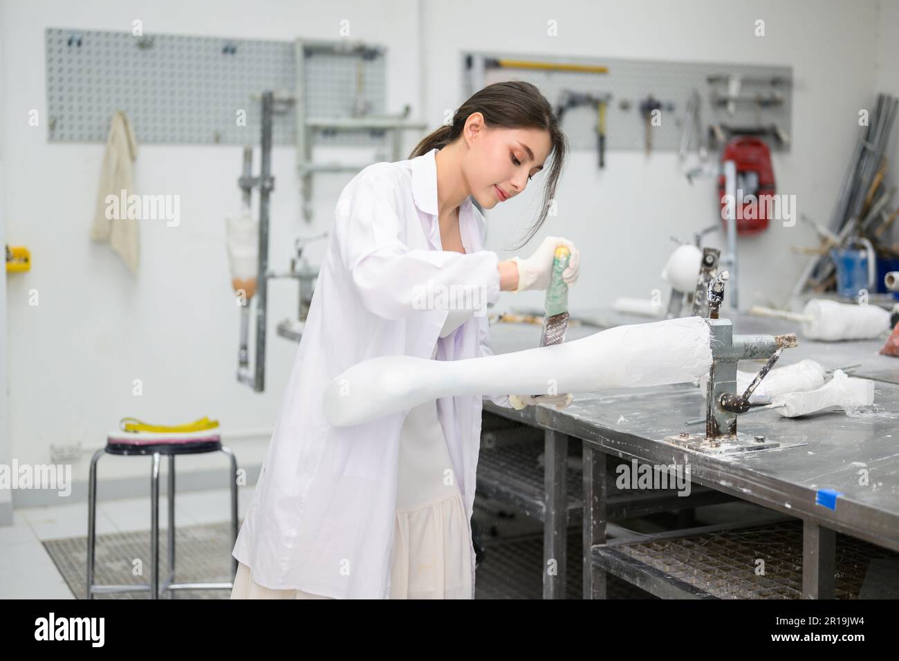 Un technicien en prothèse sculptant du plâtre moulé pour la prise en usine Banque D'Images
