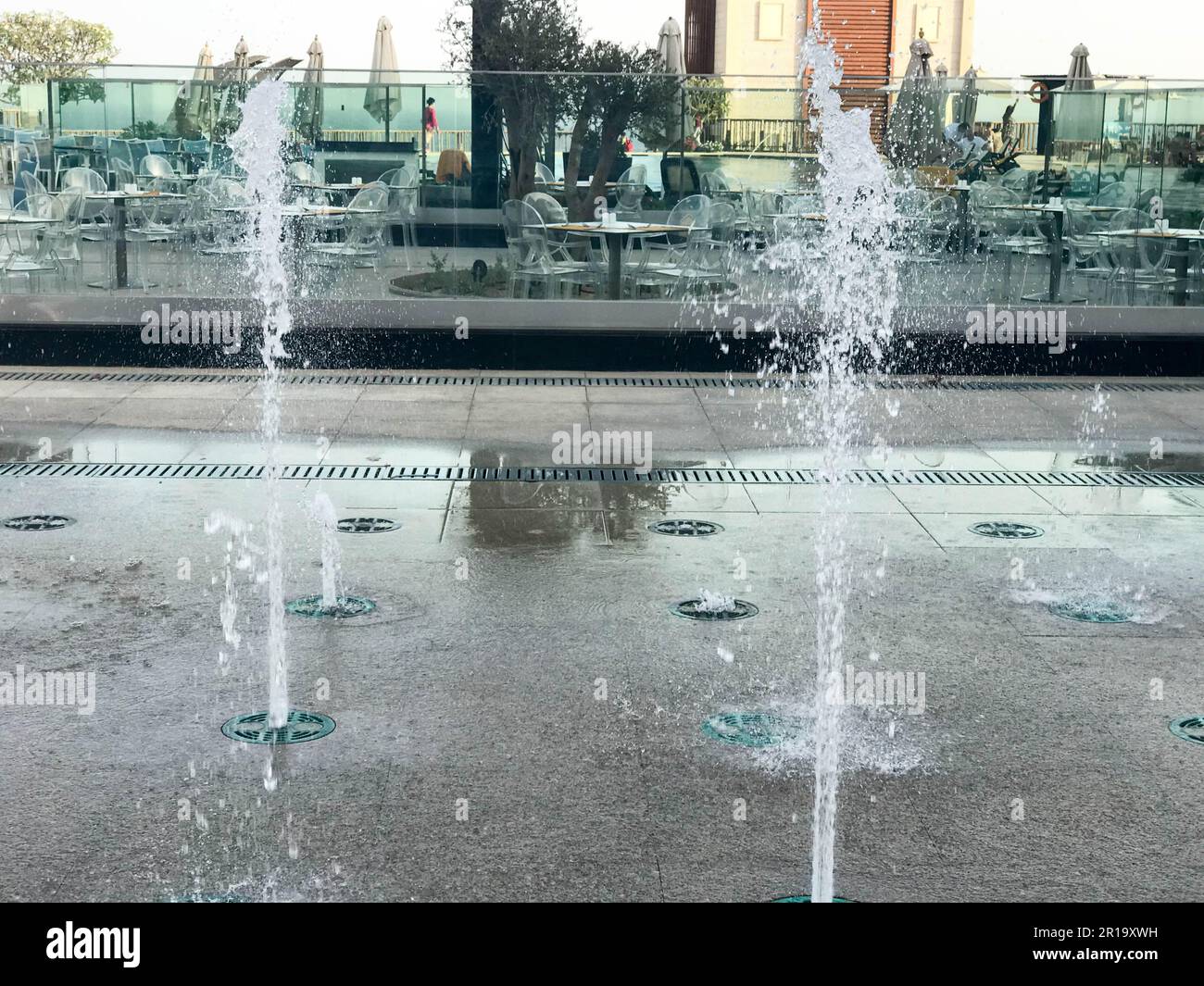 Une petite belle fontaine de chant en plein air, dans la rue. Gouttes d'eau, jets d'eau congelés dans l'air en vol sur fond d'un Banque D'Images