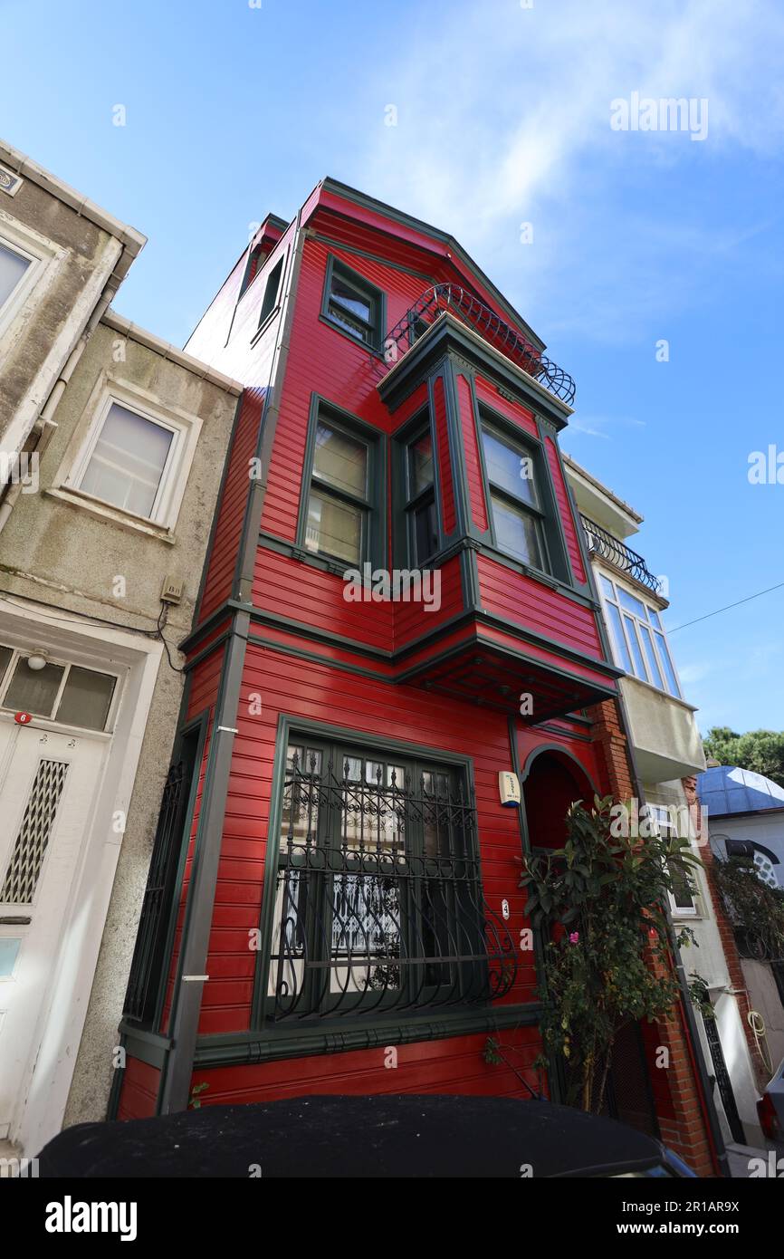 05 mars 2025, quartier Kuzguncuk, Istanbul, Turquie : Maison ottomane en bois rouge restaurée avec façade vitrée sous ciel bleu clair Banque D'Images