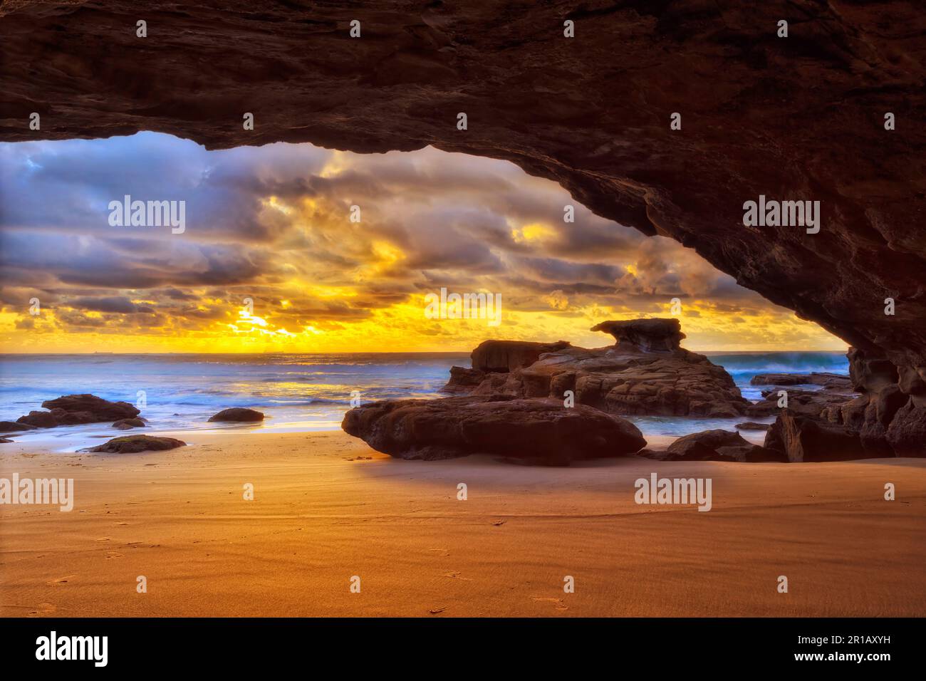 Heure d'or au lever du soleil depuis l'intérieur de la grotte de la mer sur la plage des Caves, côte du pacifique, en Australie. Banque D'Images