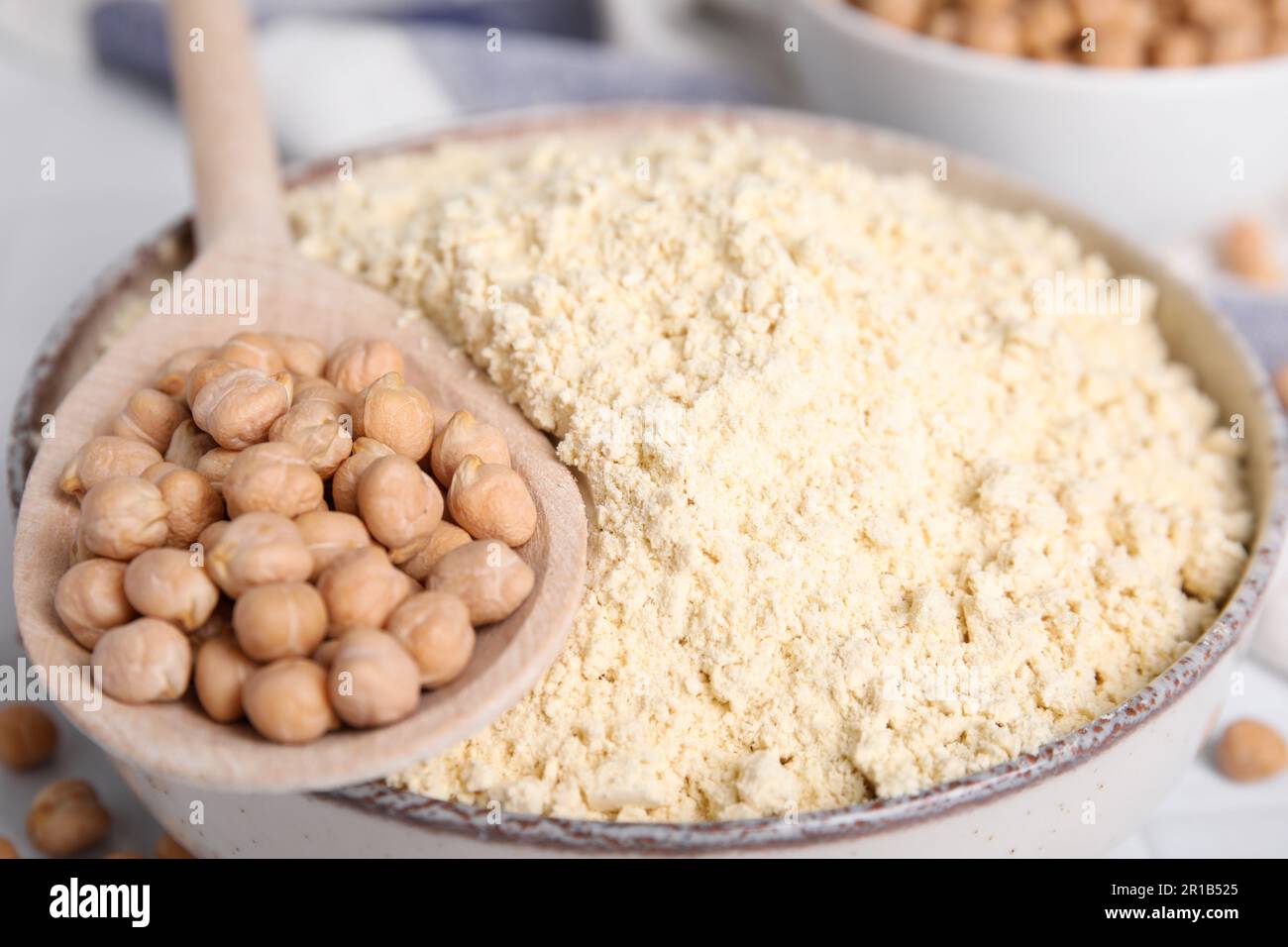 Farine de pois chiches dans un bol et graines sur table, gros plan Banque D'Images