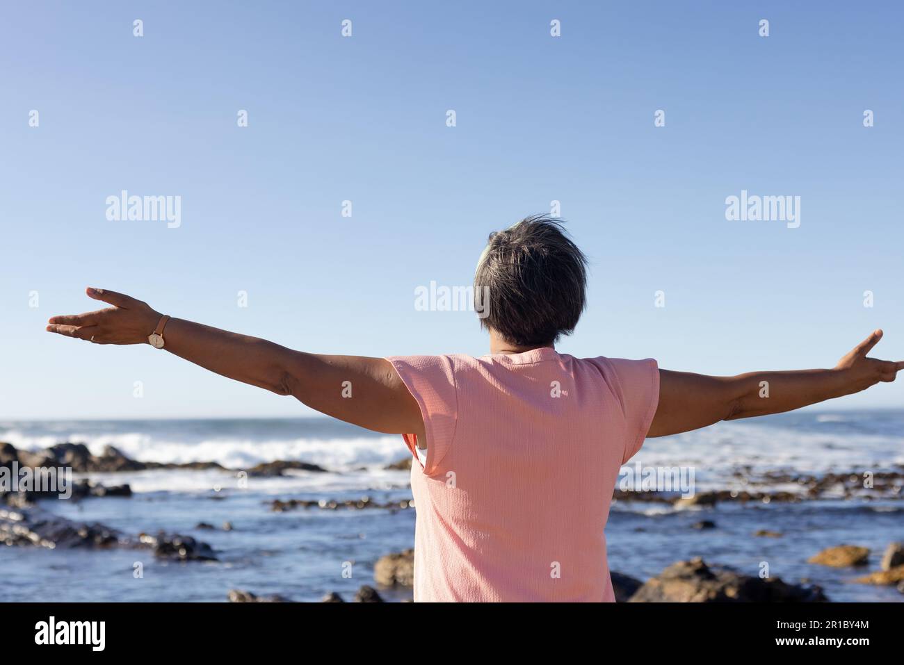 Femme afro-américaine âgée avec des armes larges au bord de la mer Banque D'Images