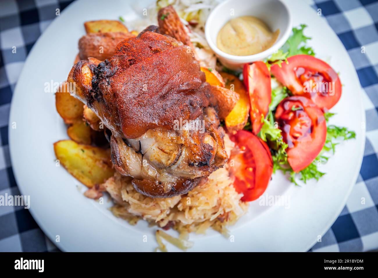 Schweinshaxe, jarret de porc cuit à la bière, chou bavarois et ail, steak de pommes de terre au persil. Banque D'Images