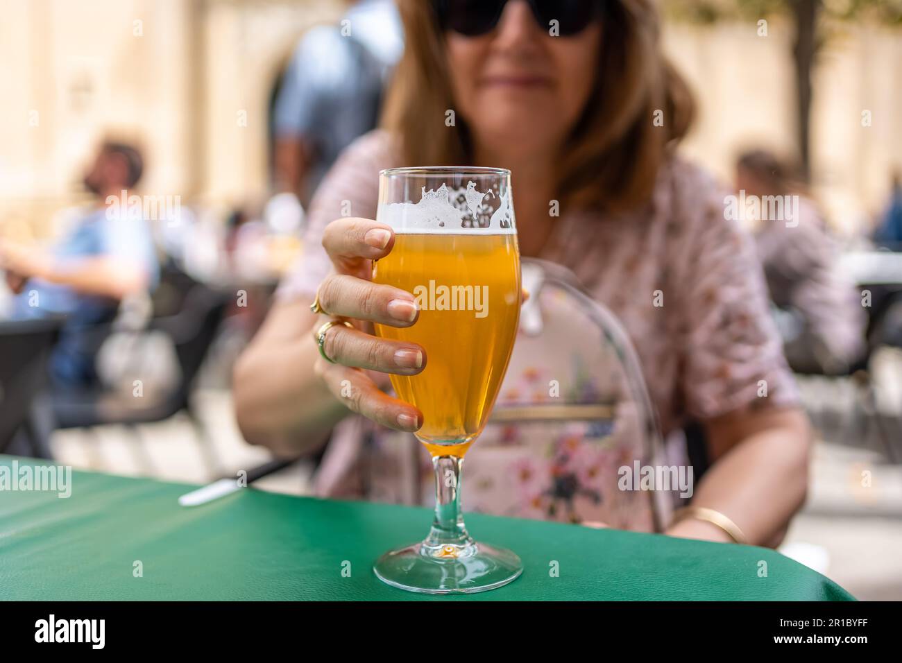 Verre de bière tenu par la main d'une femme sur une terrasse d'un bar dans la rue, Espagne. Banque D'Images