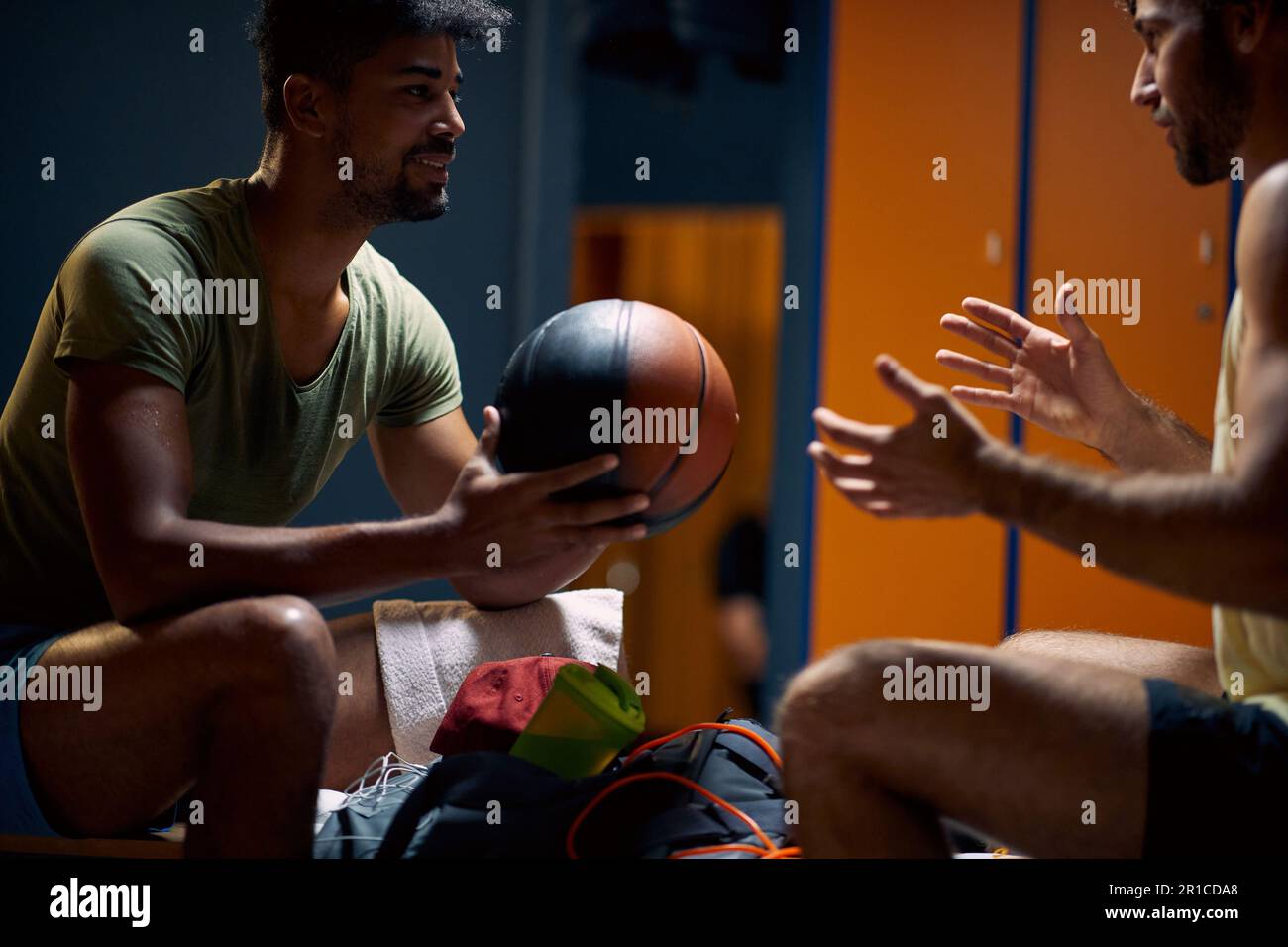 Deux jeunes joueurs ayant une conversation après un excellent entraînement, se sentant sous tension, les joueurs de basket-ball dans le dressing se reposant. Sport, concept de style de vie Banque D'Images