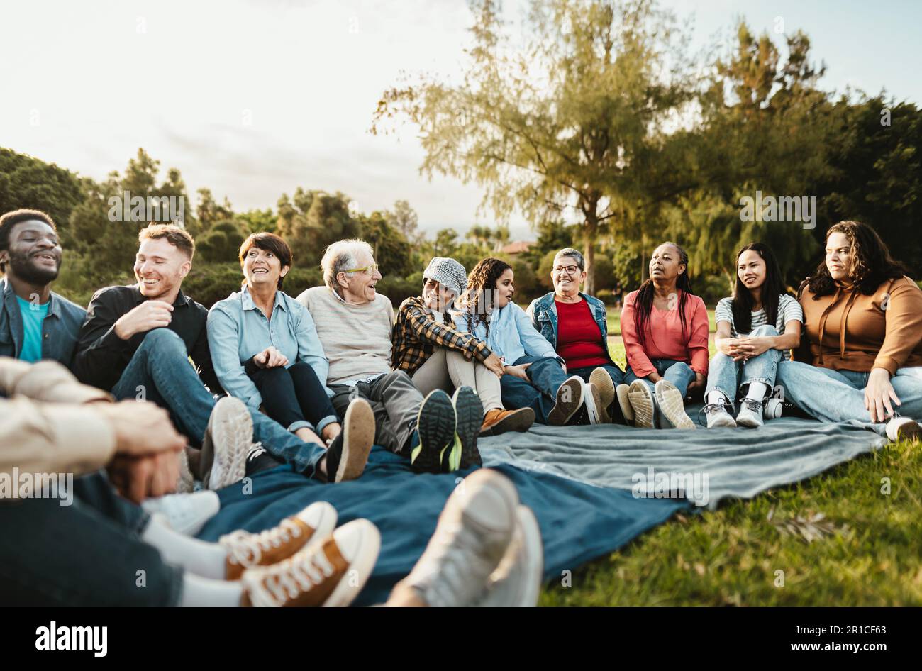 Heureux de plusieurs générations de personnes ayant plaisir assis sur l'herbe dans un parc public - diversité et amitié concept Banque D'Images