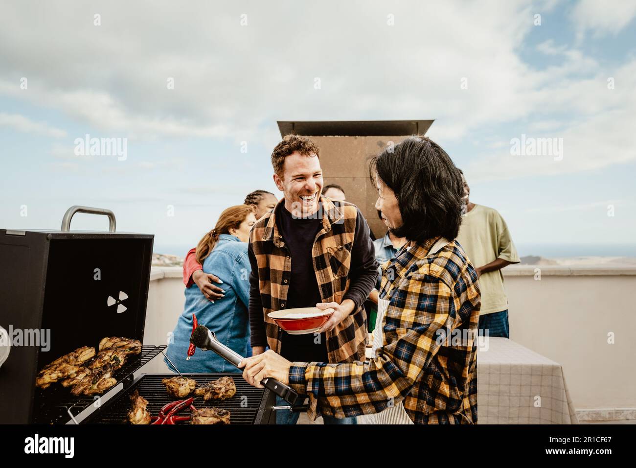 Heureux multigénérationnel personnes ayant l'amusement faire barbecue sur le toit de la maison - réunions d'été et concept de nourriture Banque D'Images