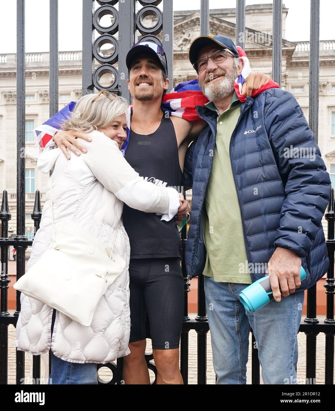 Josh Patterson, ultra-athlète, militant et personnalité de la télévision, devant les portes de Buckingham Palace, Londres, avec ses parents Sarah et Denis, après avoir terminé 76 marathons en jours consécutifs, un dans chaque ville du Royaume-Uni, pour recueillir de l'argent pour les Samaritans. Date de la photo: Samedi 13 mai 2023. Banque D'Images