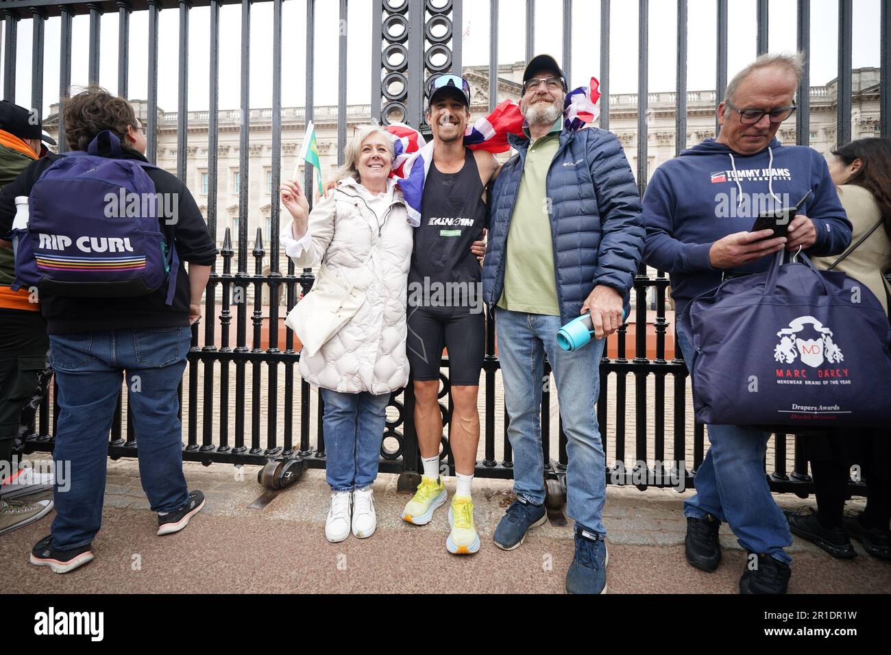 Josh Patterson, ultra-athlète, militant et personnalité de la télévision, devant les portes de Buckingham Palace, Londres, avec ses parents Sarah et Denis, après avoir terminé 76 marathons en jours consécutifs, un dans chaque ville du Royaume-Uni, pour recueillir de l'argent pour les Samaritans. Date de la photo: Samedi 13 mai 2023. Banque D'Images