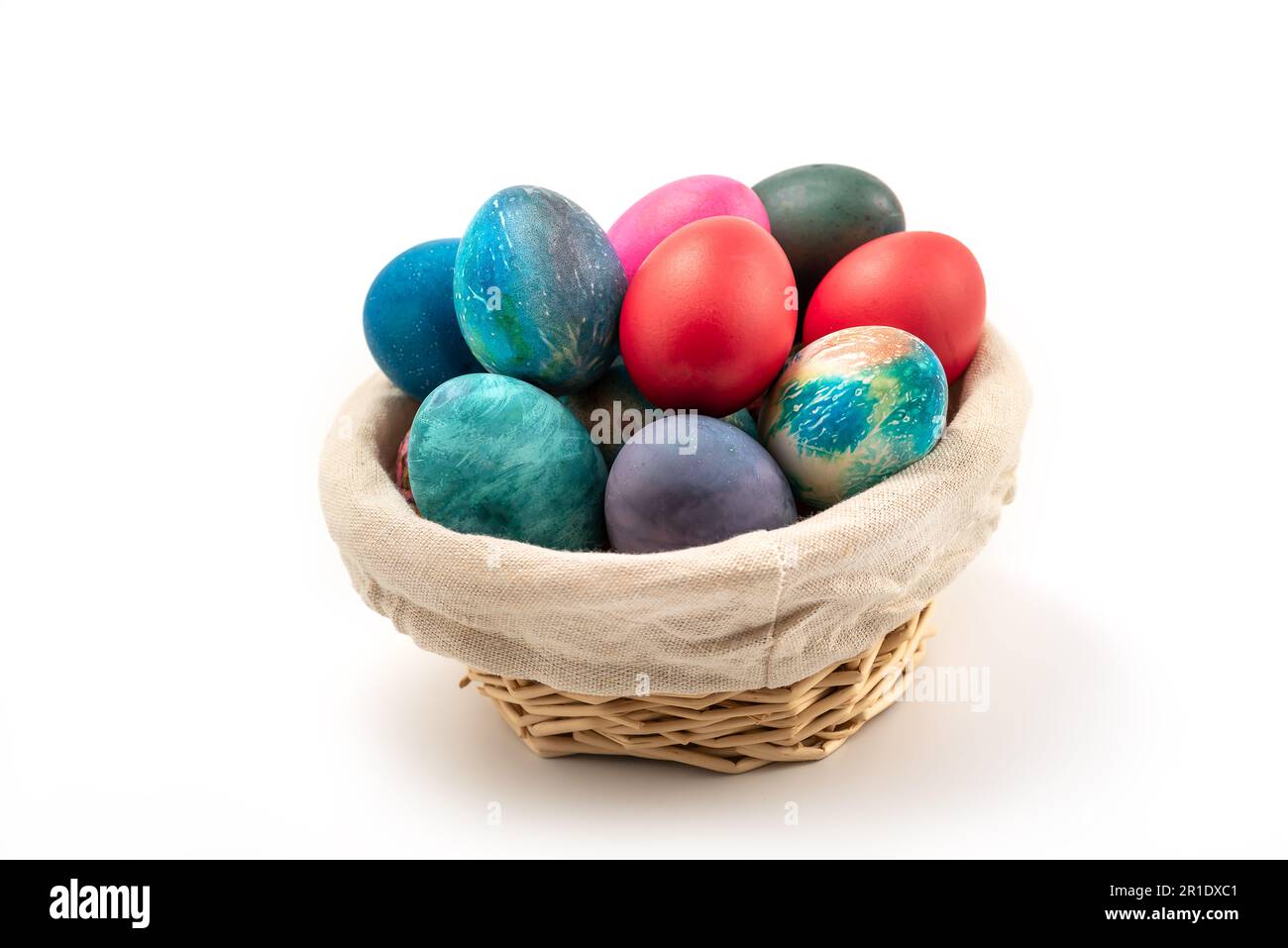 Œufs de Pâques multicolores dans le panier tissé isolé sur fond blanc avec passe-cheveux Banque D'Images