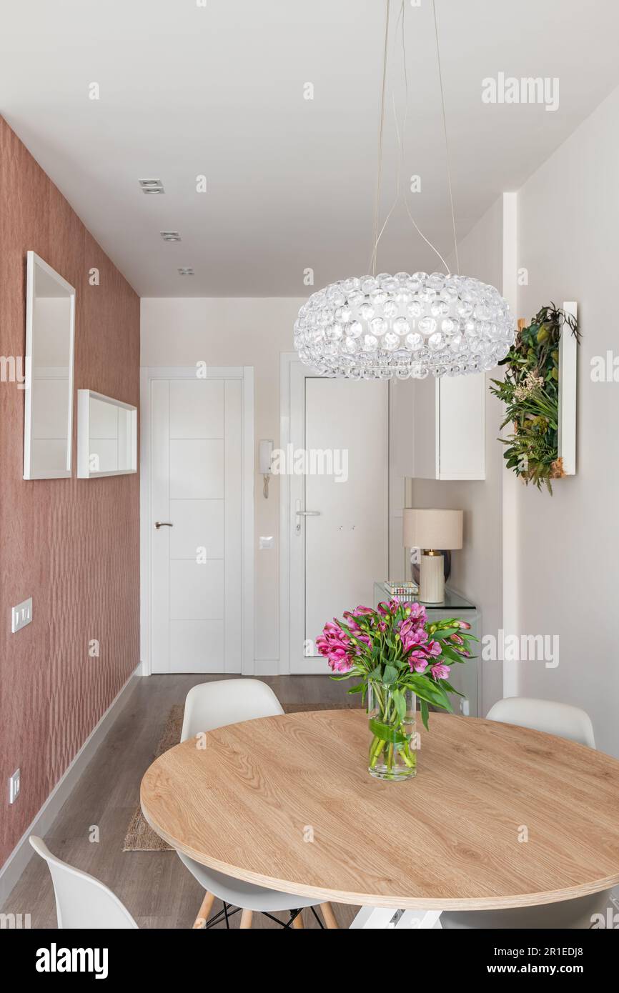 Petit salon studio avec un espace confortable de zonage, table avec des fleurs et un lustre en cristal sur le fond de la porte d'entrée et élégant Banque D'Images