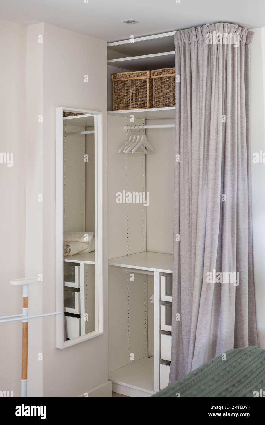Dressing confortable avec rideau gris et espace de rangement pour les objets et les vêtements dans la chambre. Concept de compact mais fonctionnel Banque D'Images
