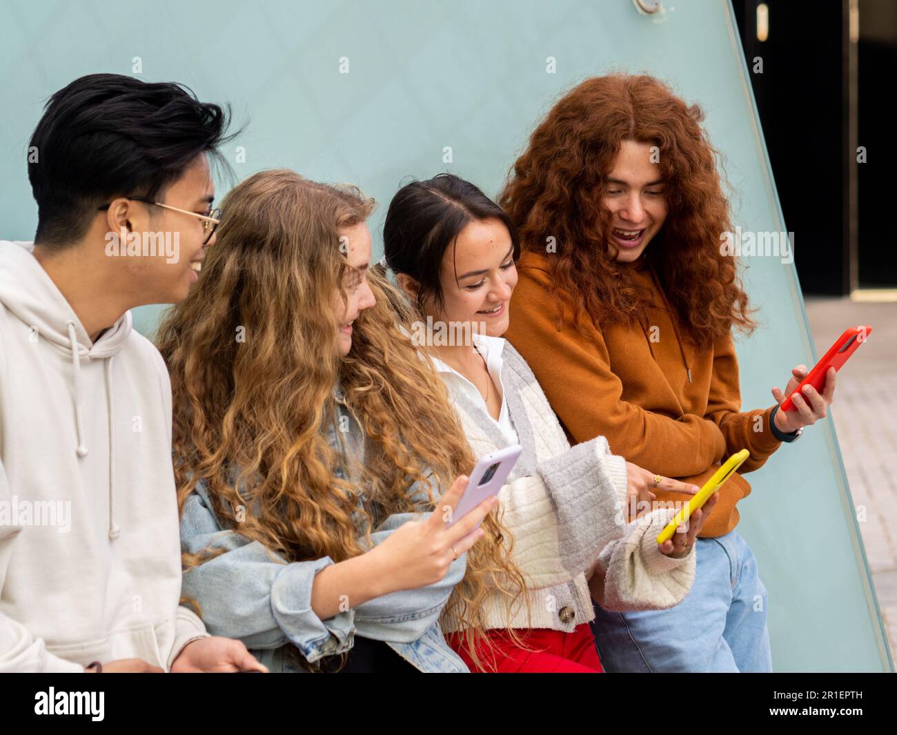 Groupe de jeunes étudiants qui regardent le smartphone souriant Banque D'Images
