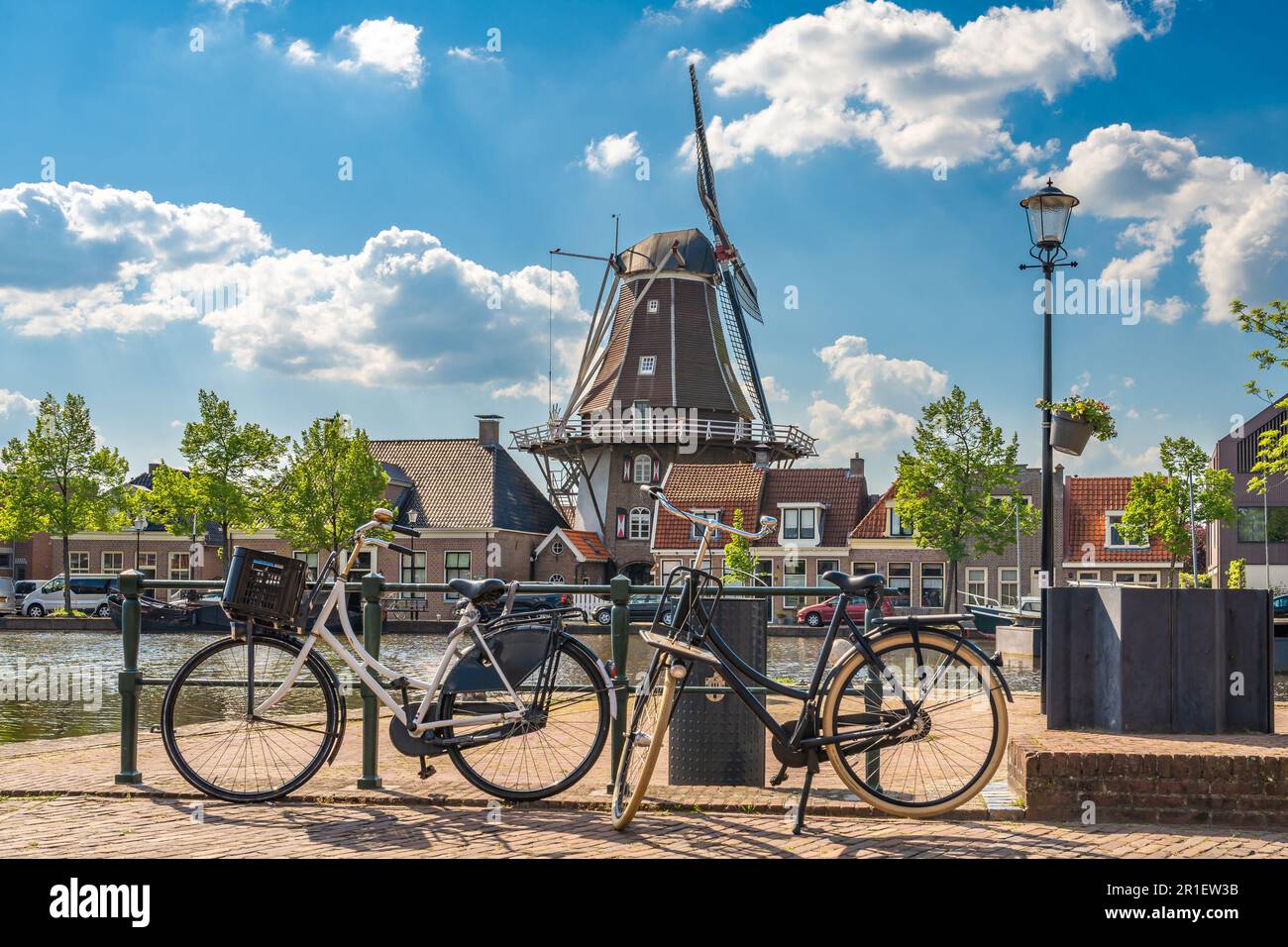 Une scène hollandaise typique avec un moulin à vent traditionnel et des vélos le long du canal dans la ville de Meppel lors d'une journée de printemps ensoleillée Banque D'Images