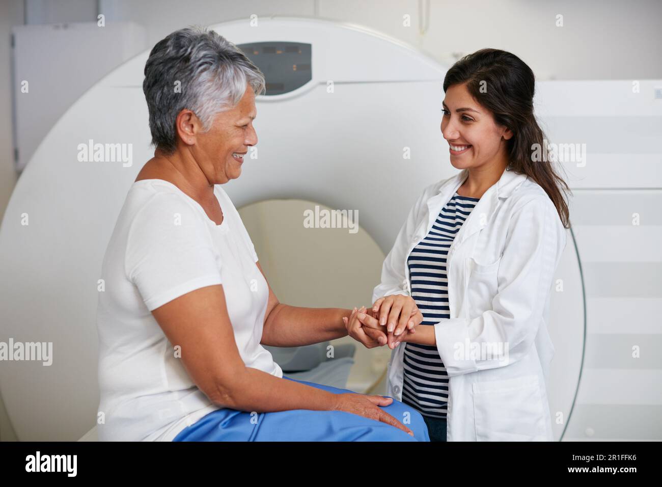 Médecin, ct scan et femme tenant les mains du patient à l'hôpital avant d'effectuer l'acquisition dans la machine. IRM, confort et professionnel de la santé heureux avec senior Banque D'Images
