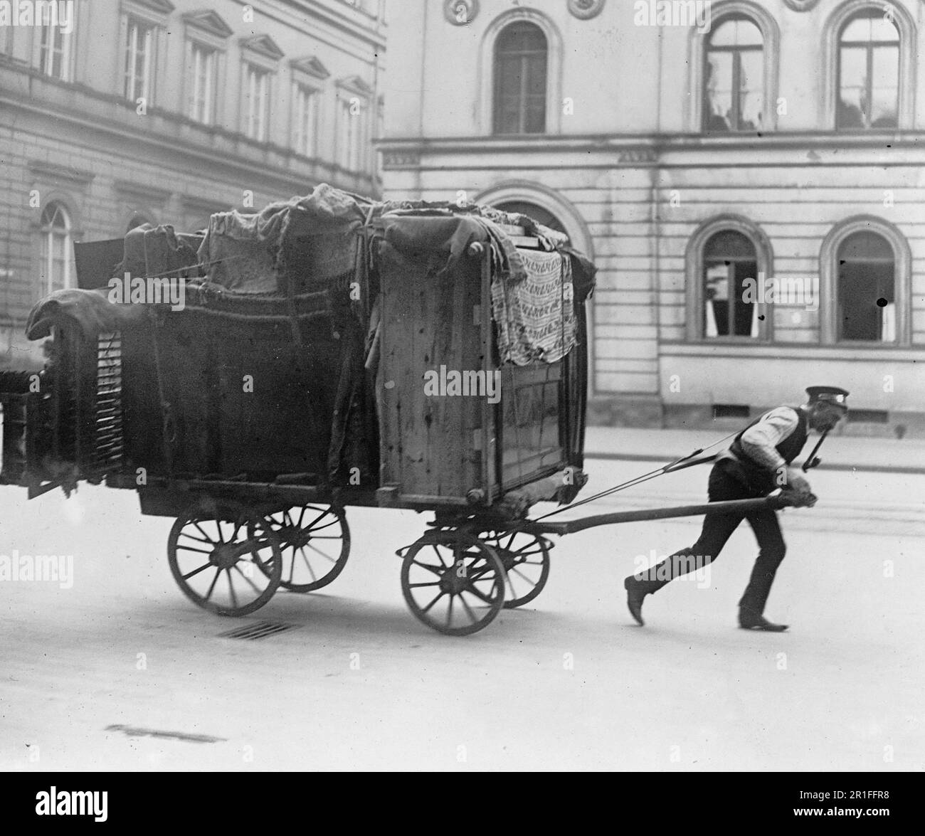 Photo d'archives: Un homme en mouvement tirant un chariot plein d'articles ménagers, en se déplaçant dans les rues d'une ville allemande ca. 1908-1919 Banque D'Images