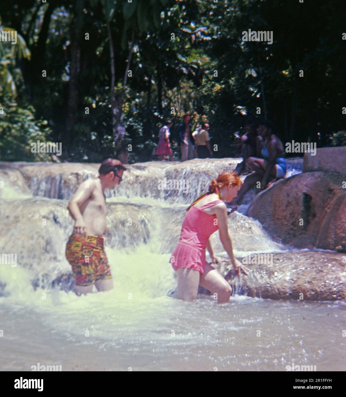 Deux touristes américains en Jamaïque marchant dans l'eau ca. 1969 Banque D'Images