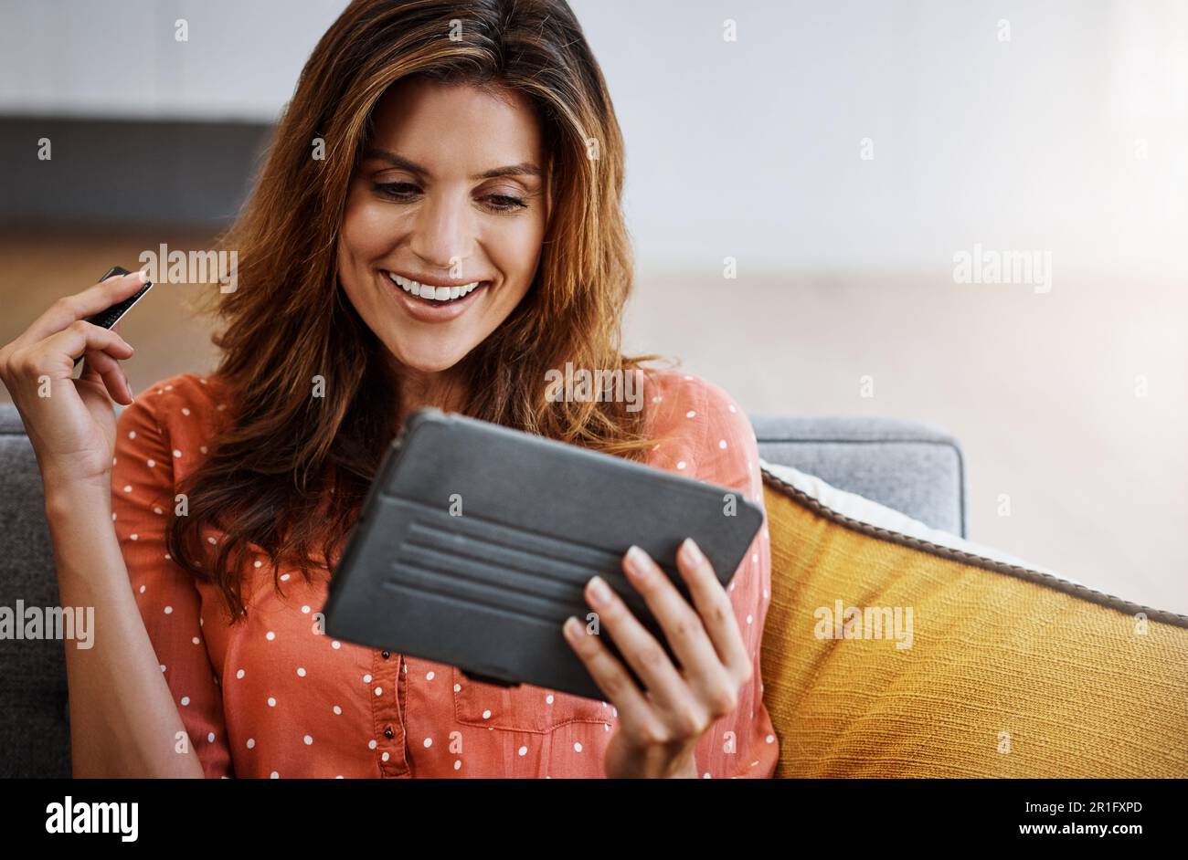 Confort et commodité, deux des plus grands avantages. une jeune femme attrayante utilisant une tablette numérique et une carte de crédit sur le canapé à la maison. Banque D'Images