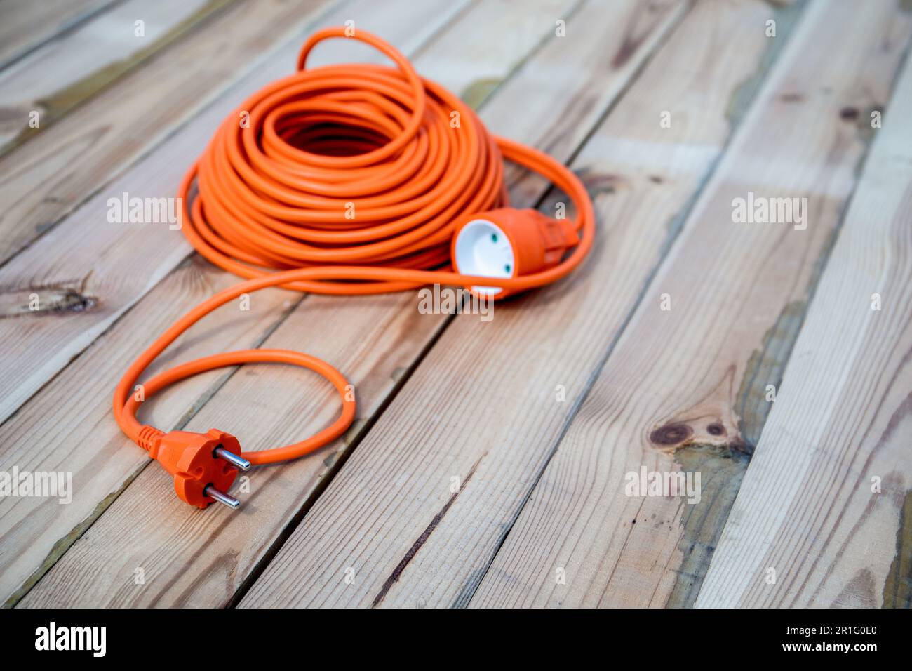 Rallonge électrique orange enroulée sur un fond en bois. Banque D'Images
