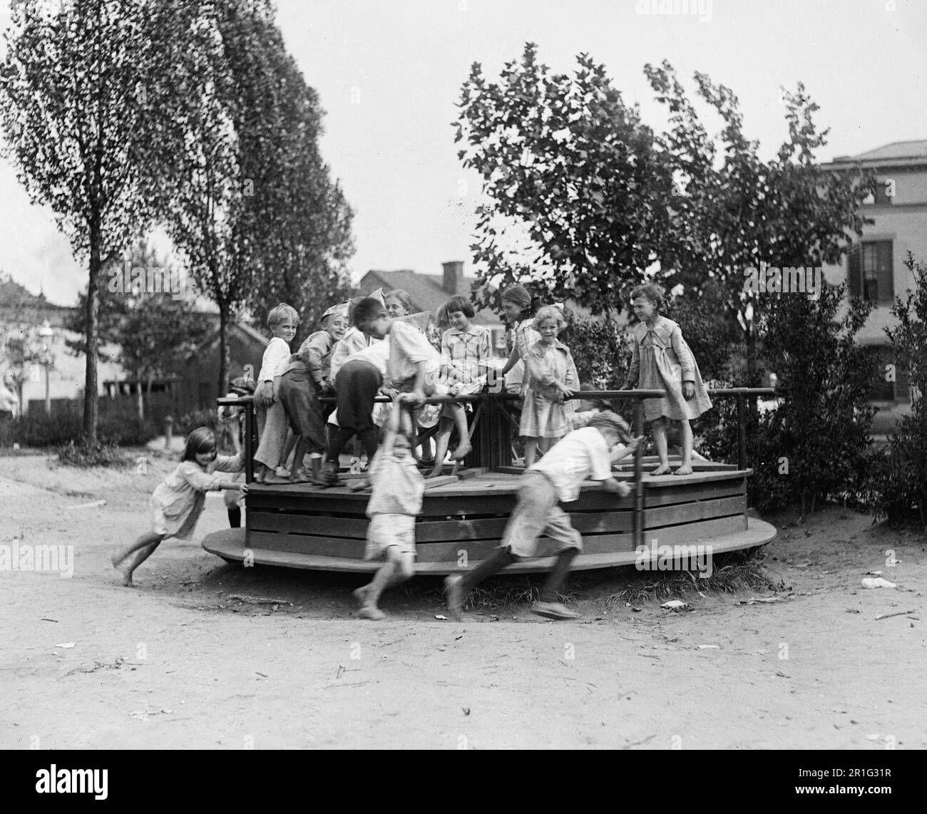 Photo d'archives: Les enfants sur un terrain de jeu jouent sur un joyeux tour de ca. 1918-1920 Banque D'Images