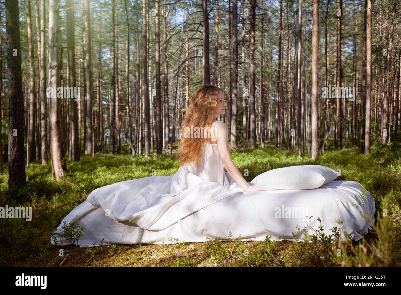 Une femme dort sur un matelas dans la forêt d'été. La fille se repose dans la nature Banque D'Images