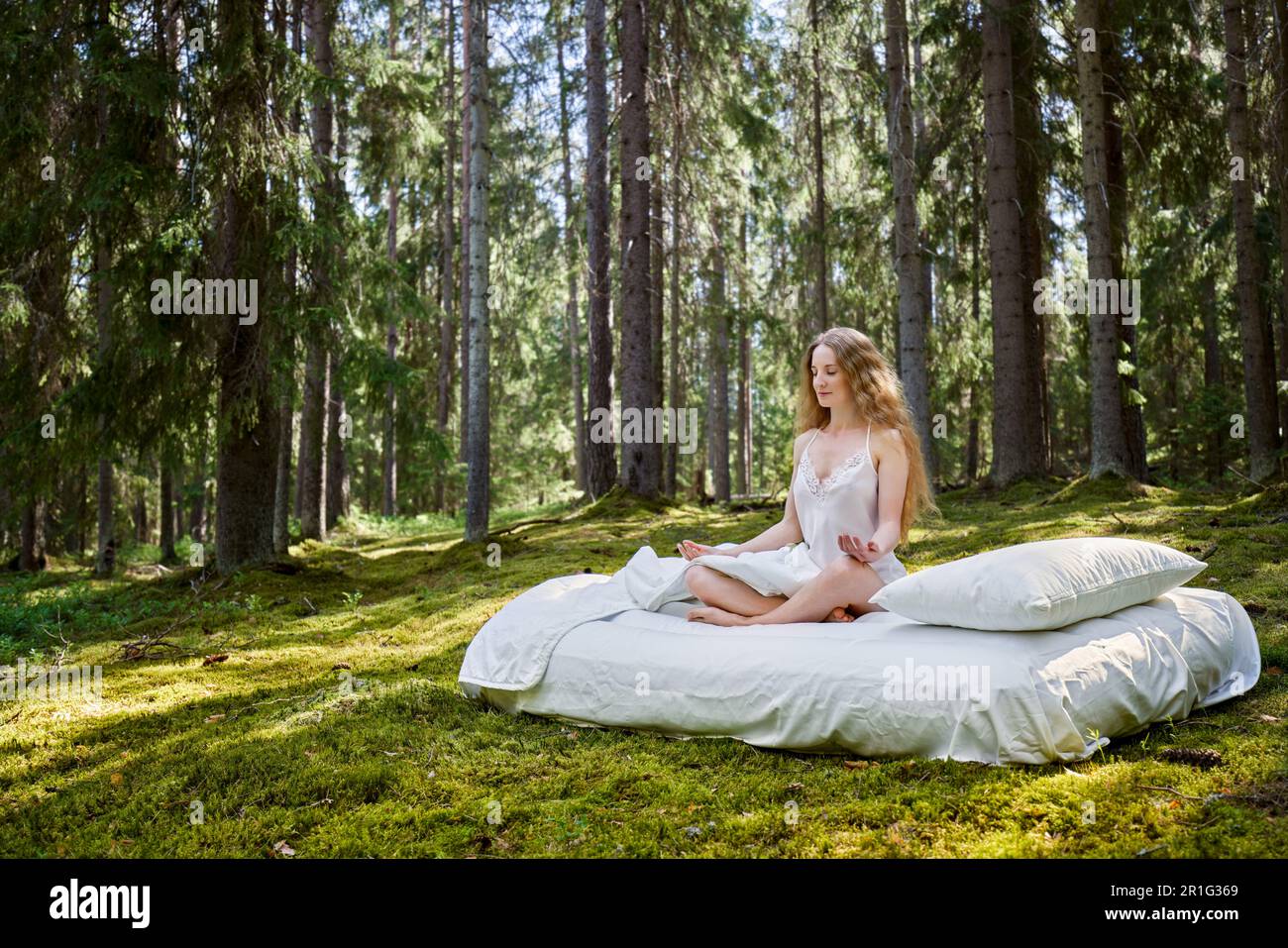 La jeune femme se repose sur un matelas en forêt estivale. La fille dort dans les bois Banque D'Images
