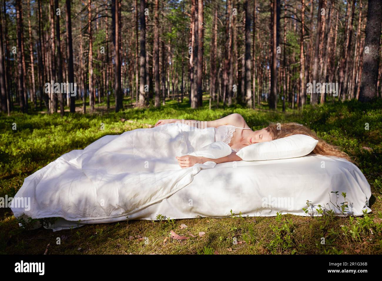 Une femme dort sur un matelas dans la forêt d'été. La fille se repose dans la nature Banque D'Images