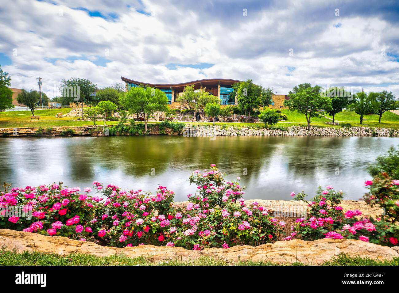 Une scène tranquille d'un parc au bord de la rivière, avec ses plantes en fleurs et ses arbres sur fond de nuages à longue exposition à San Angelo. Un beau Banque D'Images