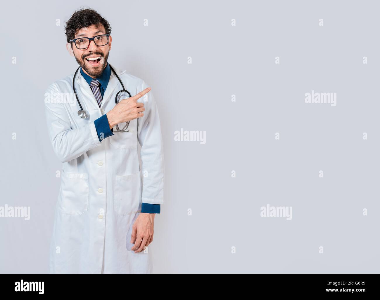 Jeune médecin pointant une promotion avec le doigt. Heureux médecin pointant sur l'espace publicitaire isolé. Heureux médecin pointant vers la droite avec le doigt Banque D'Images