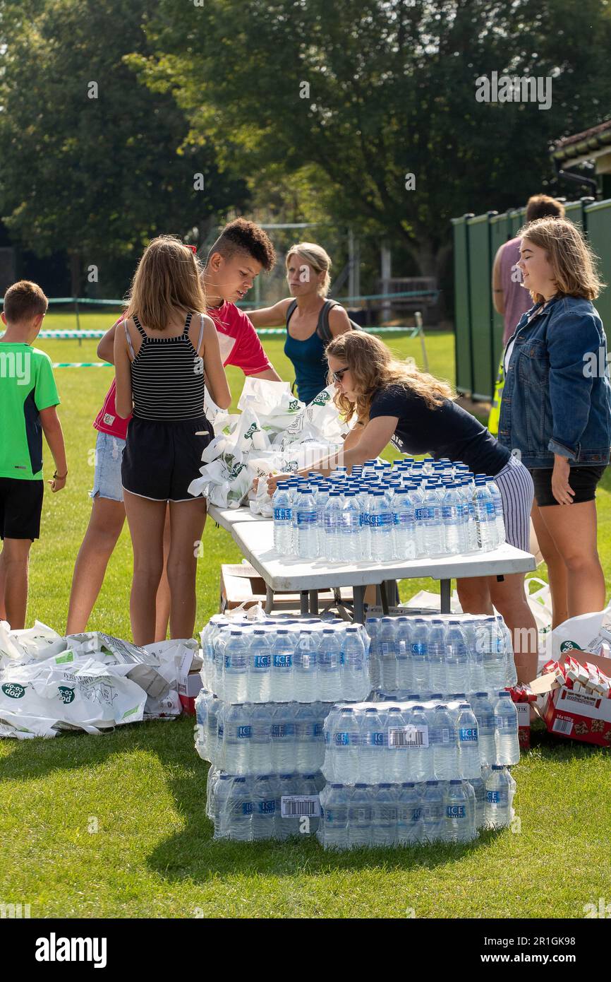 Des adolescents avec une montagne d'eau en bouteille aidant à la course de route de Framingham Flyers 10km en emballant les sacs de goodie à la fin Banque D'Images