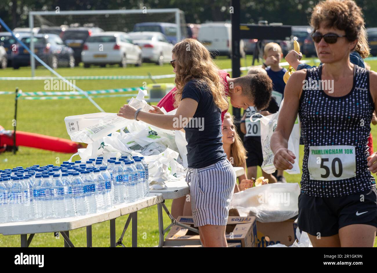 Des adolescents avec une montagne d'eau en bouteille aidant à la course de route de Framingham Flyers 10km en emballant les sacs de goodie à la fin Banque D'Images