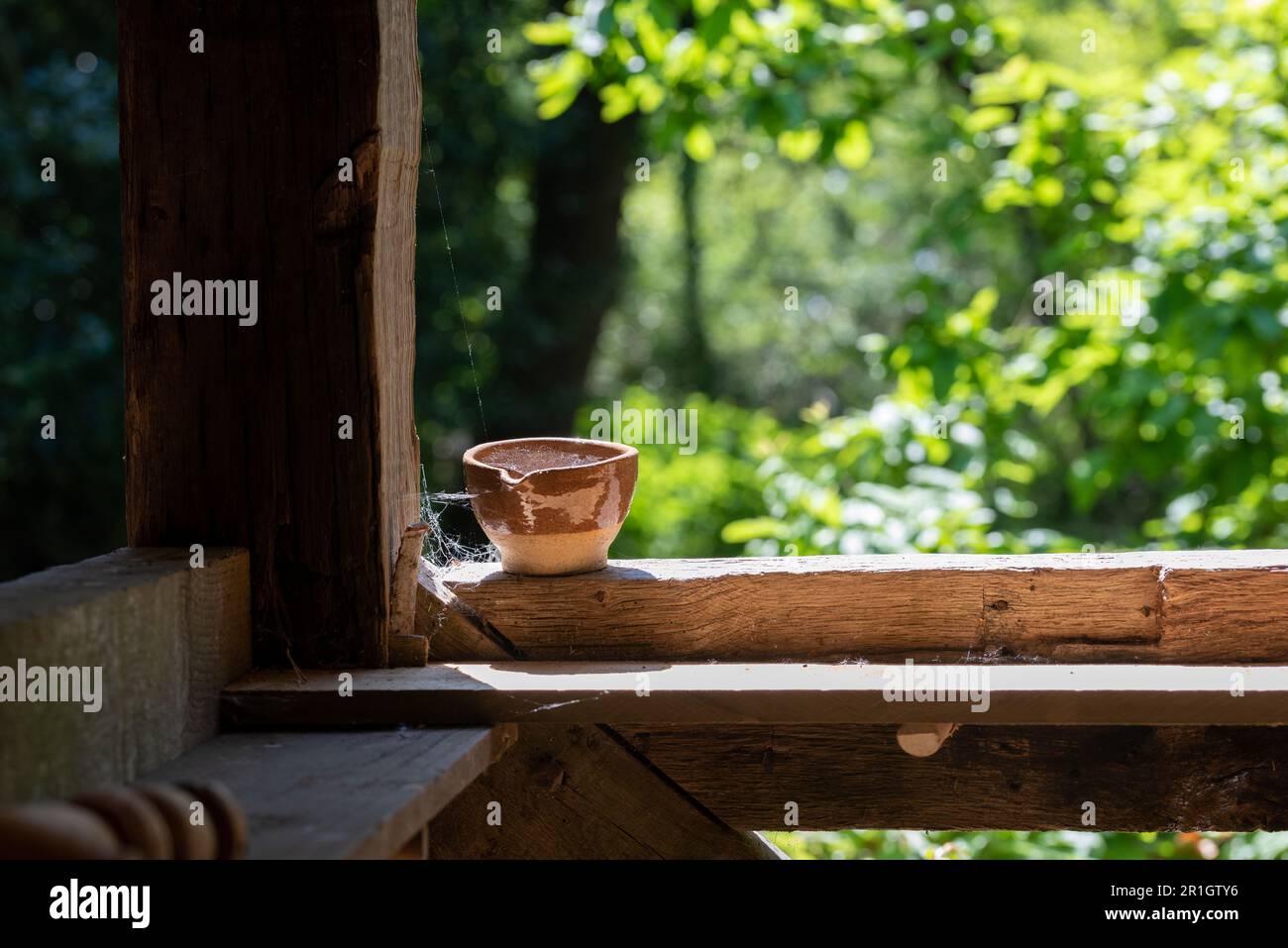 Une vieille tasse oubliée assise sur un cadre de fenêtre avec des toiles d'araignée. Banque D'Images