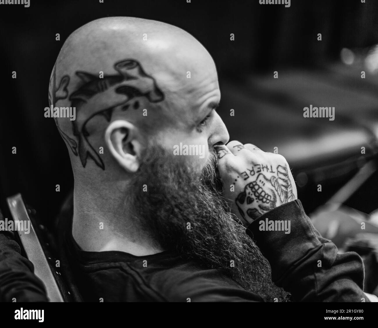 Image noire et blanche d'un homme chauve avec un tatouage dauphin sur le côté de son crâne. Banque D'Images