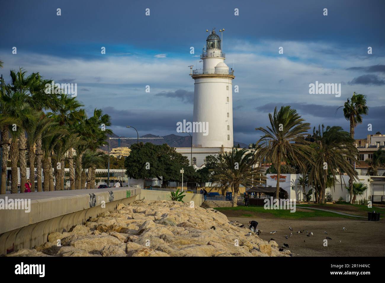 Málaga, Espagne - novembre 25 2022 : la Farola de Málaga - le phare blanc de Málaga sur la plage, entouré de palmiers en plein jour Banque D'Images