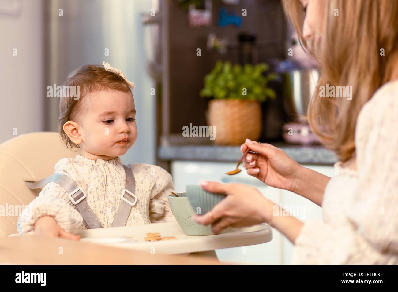 Une jeune maman qui nourrit sa petite fille avec une cuillère Banque D'Images