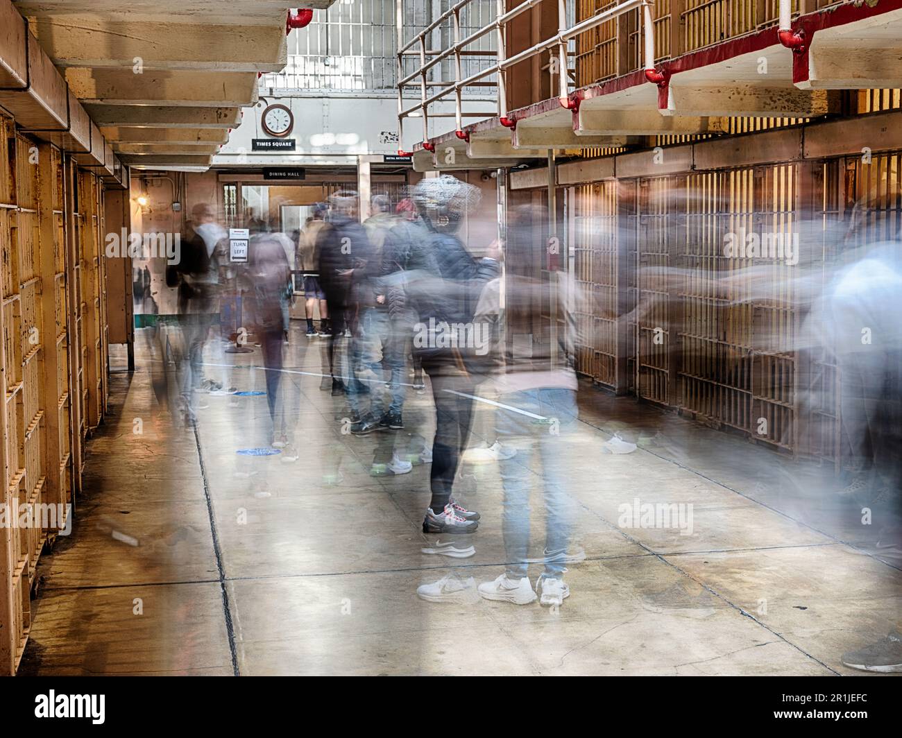 Une longue vue d'un couloir dans le pénitencier fédéral d'Alcatraz historique montre les images fantômes des personnes marchant. Banque D'Images