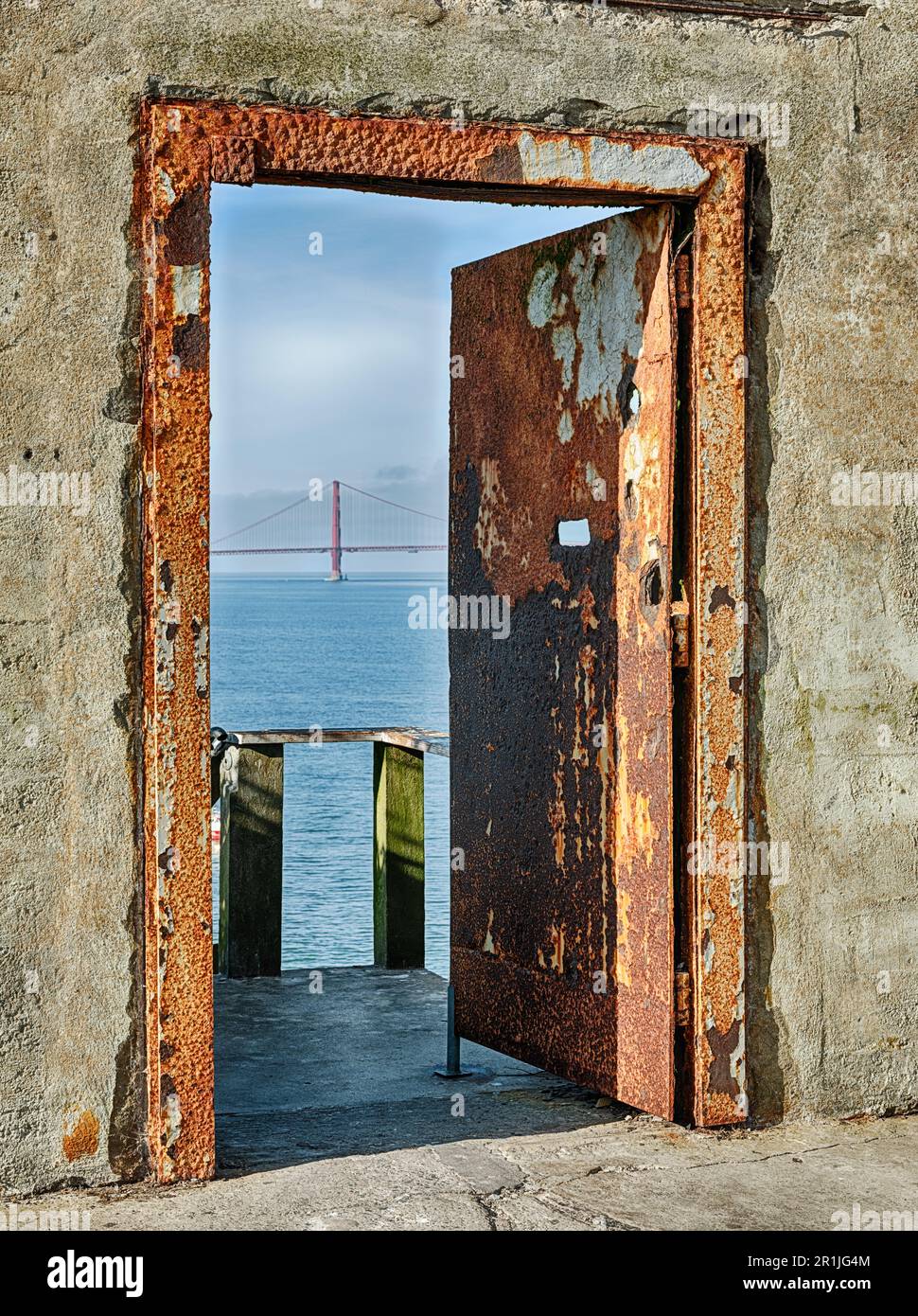 Une porte en fer rouillé dans la cour de la prison pénitentiaire d'Alcatraz donne sur la baie de San Francisco et le pont du Golden Gate. Banque D'Images