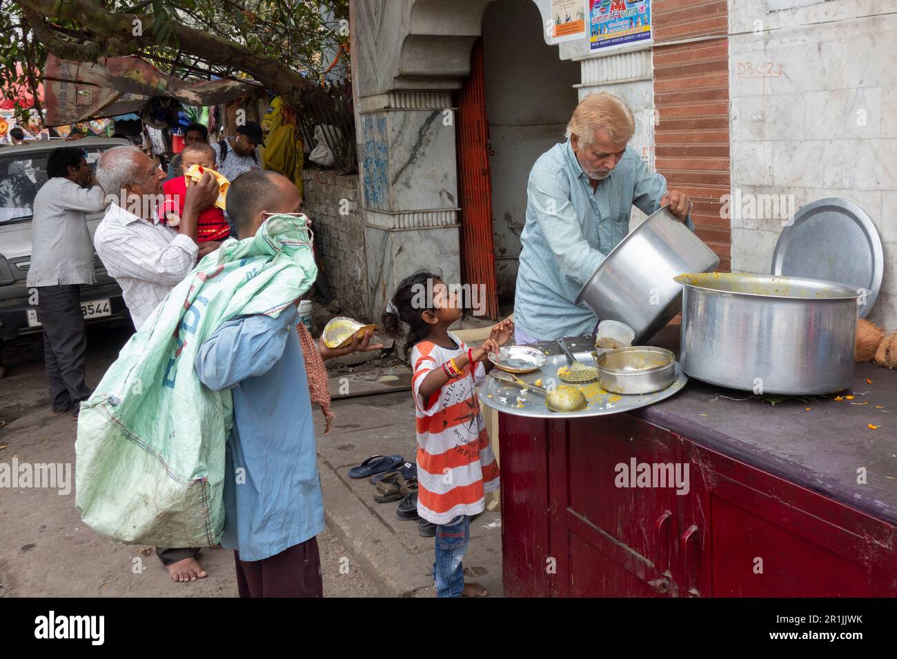 Jeune fille attendant la nourriture gratuite distribuée par un ouvrier de charité à Paharganj, New Delhi, Inde Banque D'Images