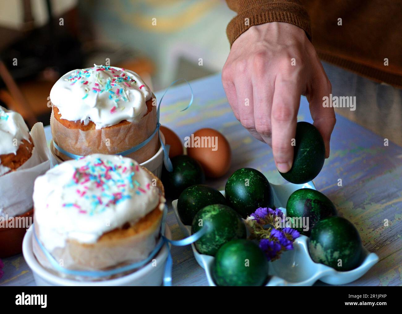 Trois gâteaux de Pâques pour Pâques sur la table. Œufs traditionnels peints sur un support. Main de l'homme tenant un œuf de pâques Banque D'Images