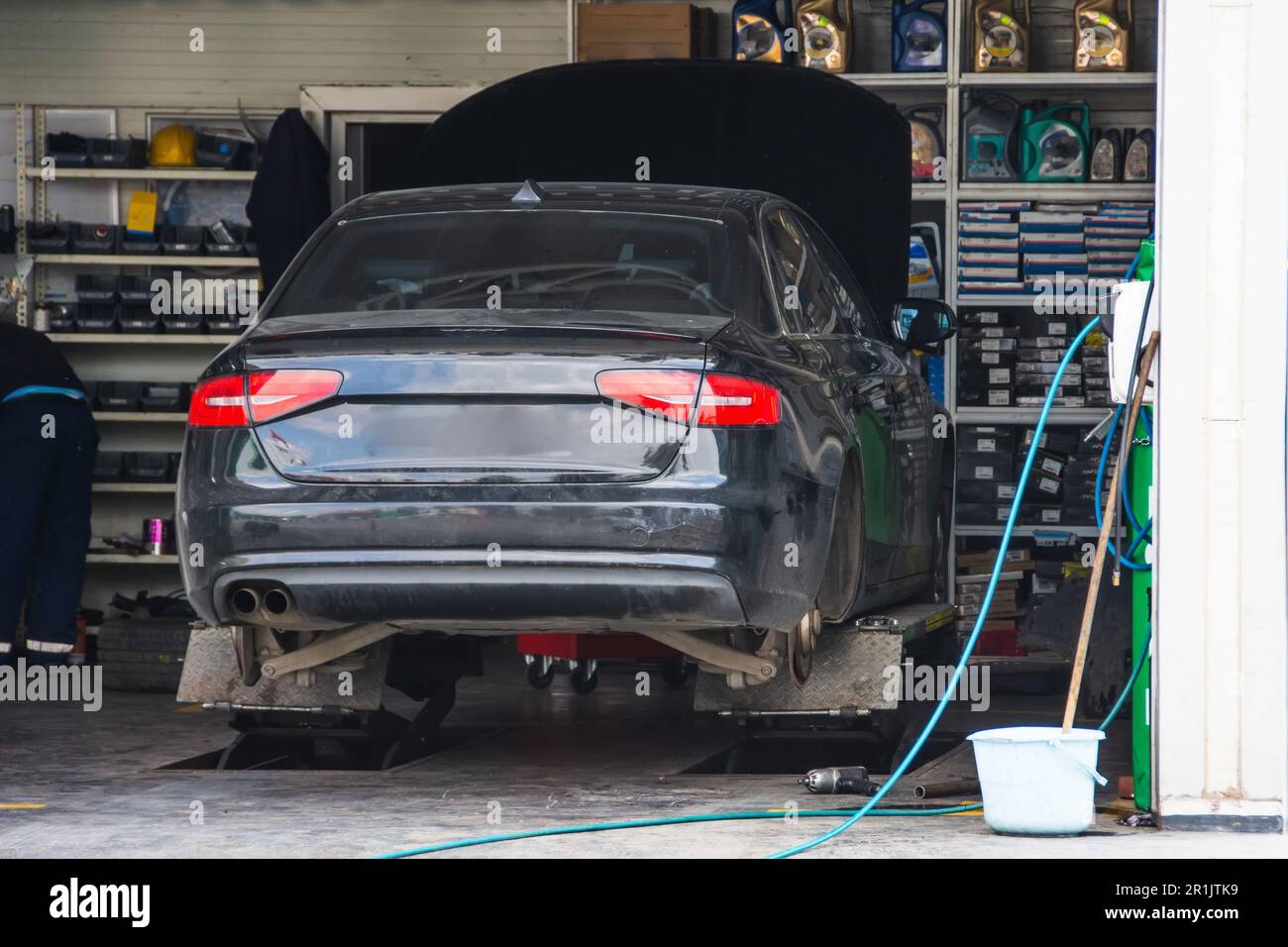 Véhicule noir soulevé au cric sans roues dans le garage pendant la réparation de la suspension et le changement de pneu Banque D'Images