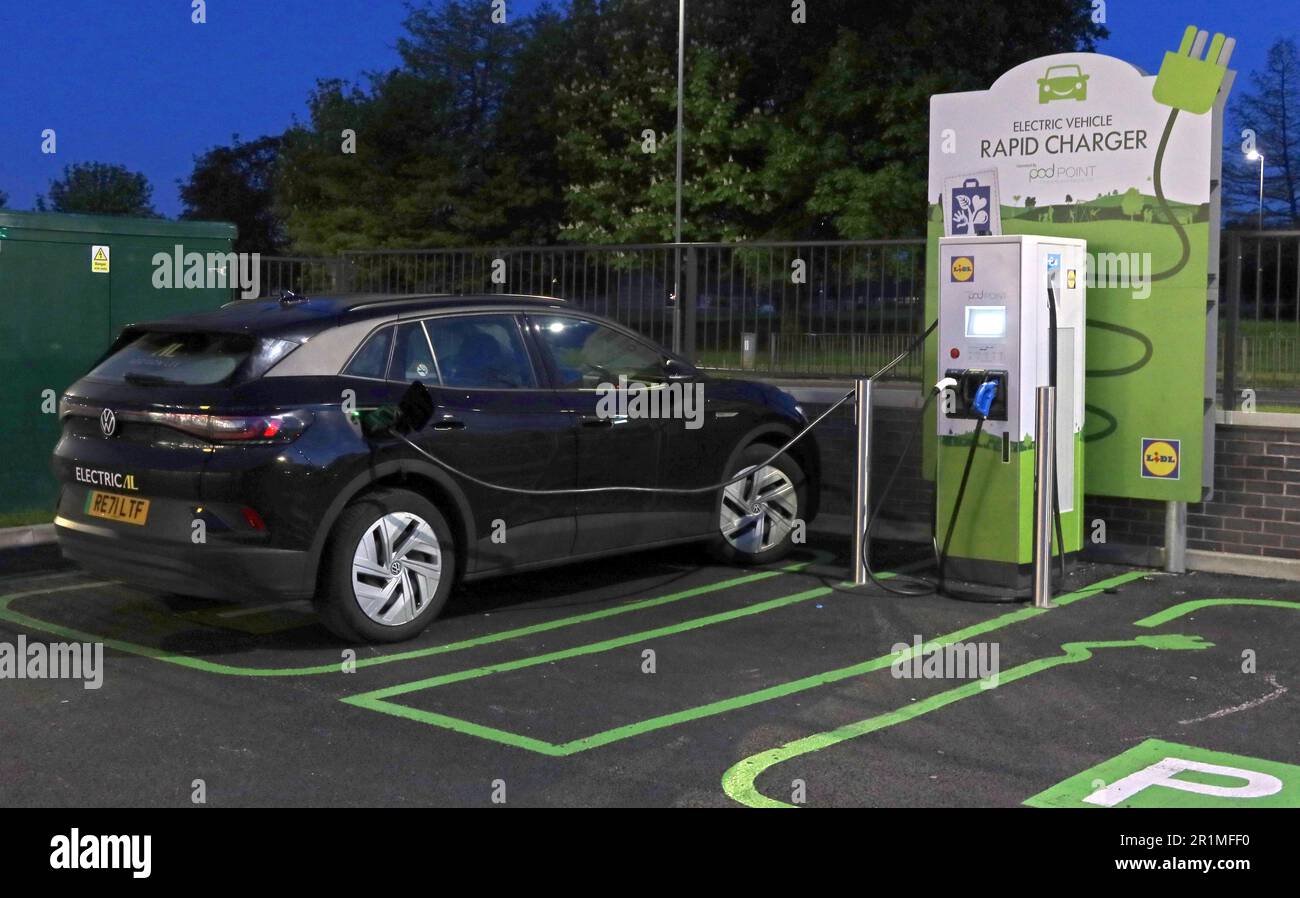 Lidl PodPoint, chargeur utilisé avec un véhicule électrique VW Volkswagen, Liverpool, Merseyside, Angleterre, Royaume-Uni, L36 3YD la nuit Banque D'Images
