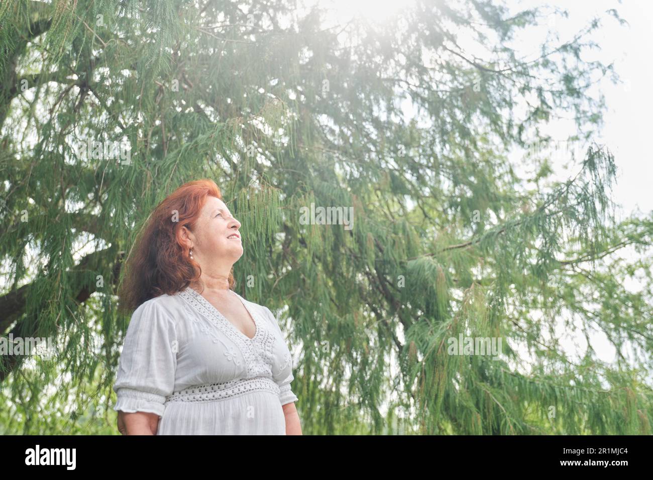 Portrait d'une femme latino-américaine aux cheveux rouges souriant, rêvant de rêver dans la nature. Composition lumineuse avec espace de copie. Concept: La paix de l'esprit et h Banque D'Images